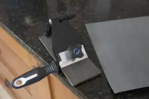 A Left-handed Knife Sharpening System (EZE-LAP stone) on a counter top with a blade on it.