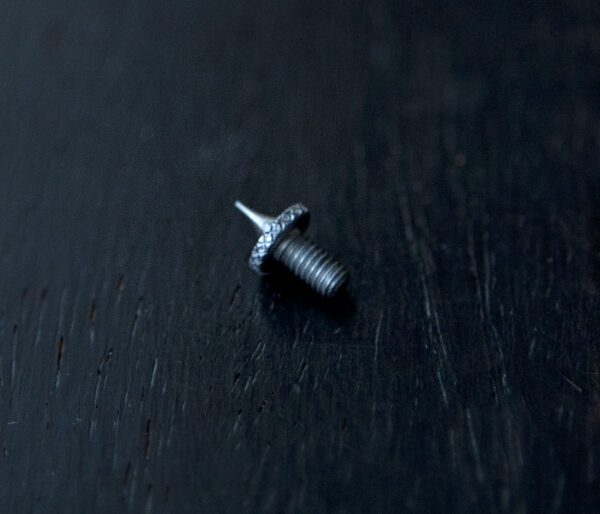 A small screw sitting on top of a black surface.