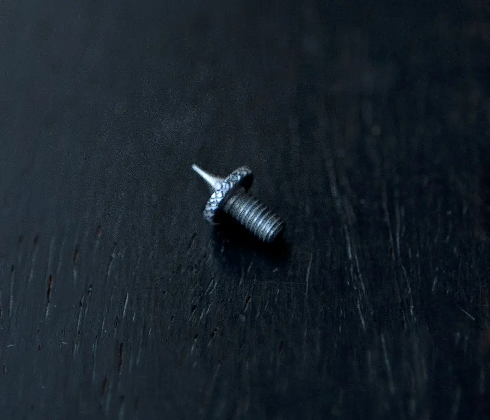 A small screw sitting on top of a black surface.
