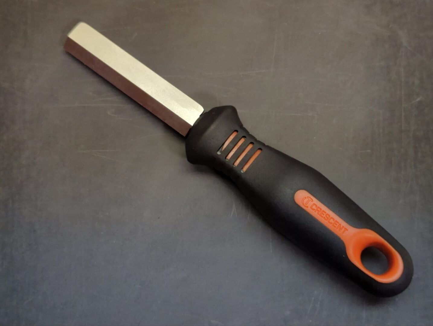 A Knife (Right-handed) with an orange handle on a black surface.