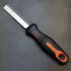A Left-handed Knife with an orange handle on a black surface.